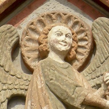 Steinrelief eines Engels mit Heiligenschein an einer Kirchenfassade