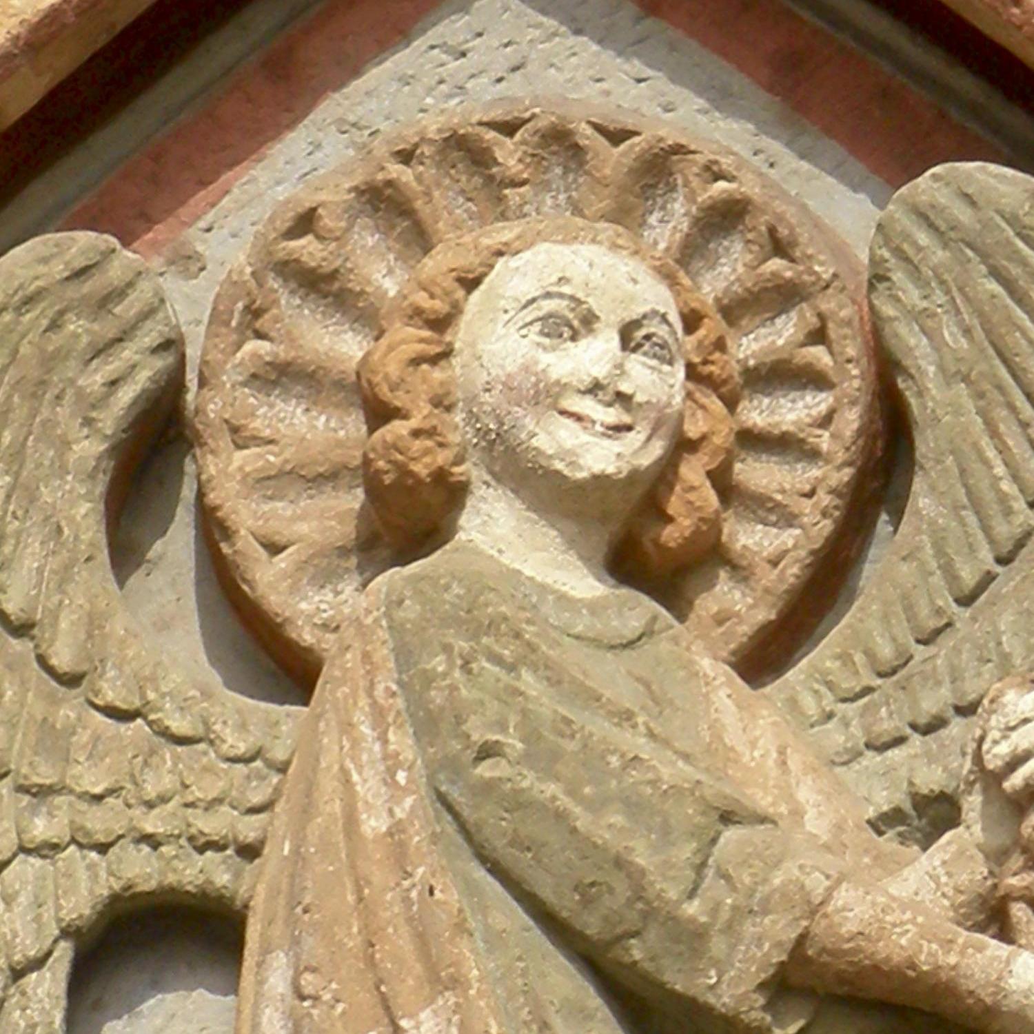 Steinrelief eines Engels mit Heiligenschein an einer Kirchenfassade